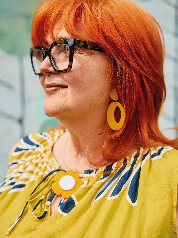 a woman with red hair wearing a yellow shirt and glasses